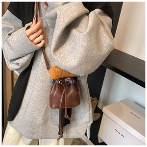 Detail view of mini dark brown PU leather bucket bag with plush charm and drawstring closure