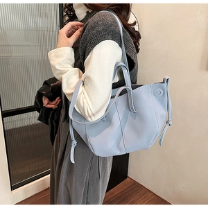 Detail view of light blue PU leather tote bag with decorative side knots and long shoulder strap