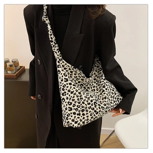 Close-up of leopard print canvas crossbody bag with thick shoulder strap on model