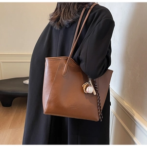 Détail du sac cabas en similicuir marron avec un pendentif sport de baseball unique