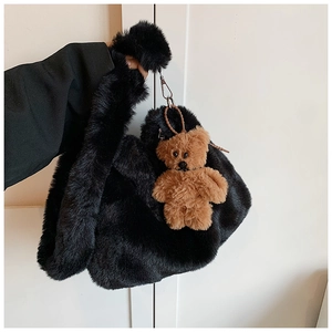 Détail de la texture en fausse fourrure noire du sac avec breloque d'ours marron