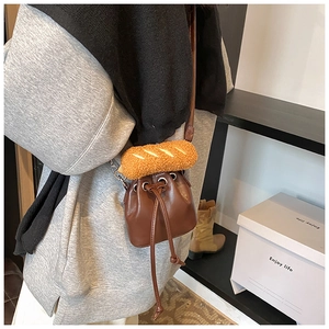 Detail view of dark brown leather bucket bag with a cute plush bread decoration