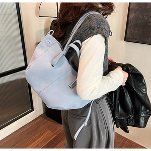Fashionable PU leather tote bag in light blue shown worn on shoulder in home setting