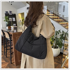 Detail of a black quilted dumpling bag featuring a minimalist padded nylon design