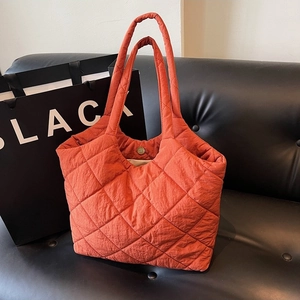 Fashionable orange quilted tote bag with diamond pattern and large capacity on black sofa