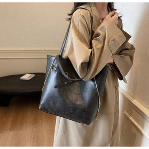 Detail of a large black leather tote bag with gold zipper and stylish buckle accents