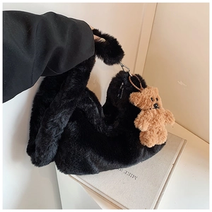 Détail d'un sac à bandoulière en peluche noire avec pendentif ours brun mignon