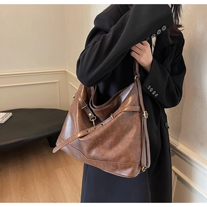 Detail of vintage brown PU leather tote bag with metallic hardware and adjustable strap
