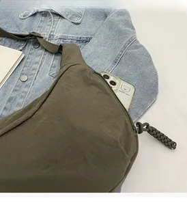 Detail of olive green nylon bag showing spacious zipper pocket and woven rope puller