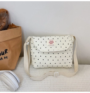 Dettaglio di borsa a tracolla in cotone trapuntato bianco a pois neri con cinturino