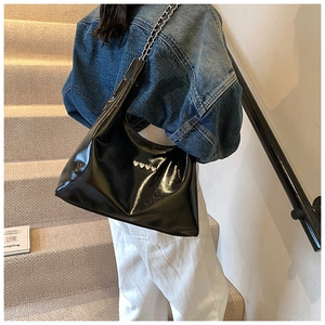 Dettaglio borsa hobo nera lucida con rivetti a cuore argento e tracolla a catena
