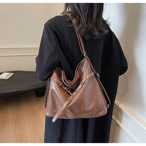Detail of vintage brown PU leather tote bag with metallic buckle on a model shoulder