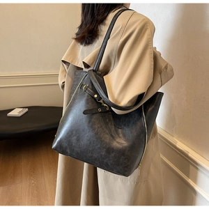 Deep grey oil-wax faux leather tote bag with gold zipper and buckle shown on a model