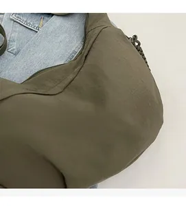 Detail of olive green nylon dumpling bag showing pleated texture and woven zipper pull cord
