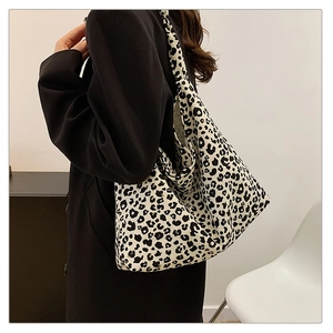 Detail of a large leopard print tote bag styled with a minimalist black coat for women