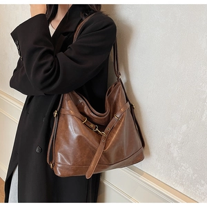 Detail of vintage brown PU leather hobo bag with adjustable buckle and bronze hardware