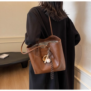 Détail d'un sac cabas en similicuir marron avec pendentif décoratif sur le thème du baseball
