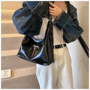 Dettaglio borsa sottobraccio in pelle verniciata nera con cuori metallici e tracolla a catena
