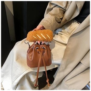 Detail of brown leather bucket bag featuring a unique plush baguette-shaped handle