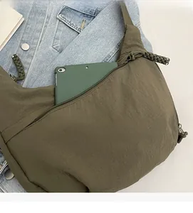 Detail of the green crossbody bag showing side zipper pocket and large interior capacity