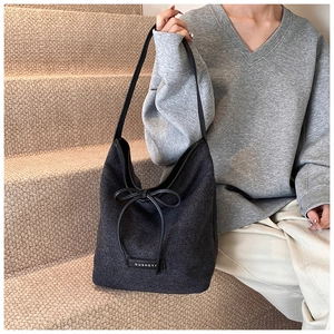 Detail of grey hobo bag with black leather bow accent and brand label on strap