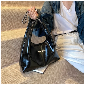 Dettaglio della borsa hobo in vernice nera con borchie a cuore argentate e catena