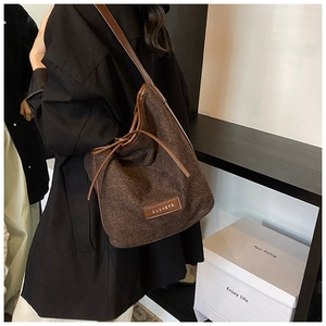 Detail view of brown corduroy shoulder bag with leather drawstring and OUBNEYA logo