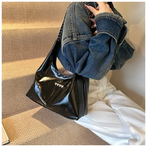 Borsa in pelle lucida nera con borchie a cuore argentate indossata da una modella casual