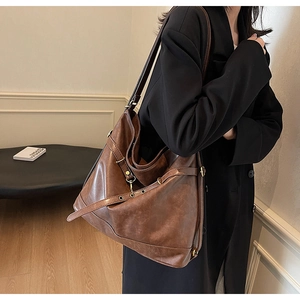 Detail of a dark brown PU leather Hobo bag featuring metal buckles and decorative straps