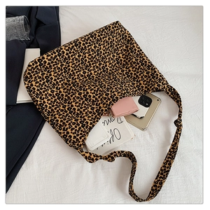 Detailed view of leopard print tote bag interior capacity with essentials on white background