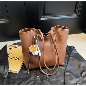 Grand sac cabas en cuir marron foncé avec breloques de baseball sur fond sombre élégant