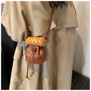 Detail of brown PU bucket bag with unique plush bread ornament on khaki trench coat