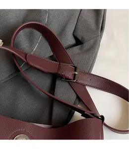 Detail of adjustable burgundy lychee-textured leather shoulder strap with dark gunmetal buckle