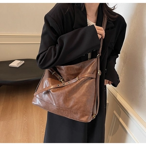 Detailed view of dark brown PU leather shoulder bag with vintage buckles on a model