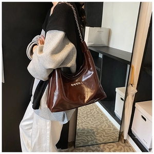 Dettaglio borsa hobo marrone scuro con rivetti a cuore e tracolla in catena e pelle