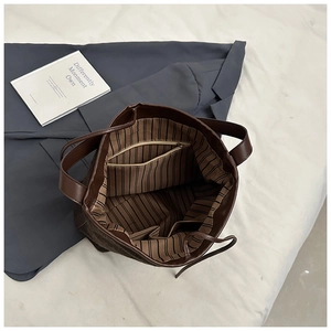 Detail view of large brown tote bag with striped lining and internal zipper pocket