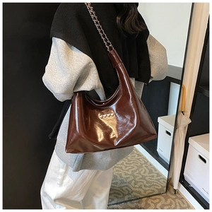 Dettaglio della borsa a spalla in pelle PU lucida marrone con cuori metallici decorativi