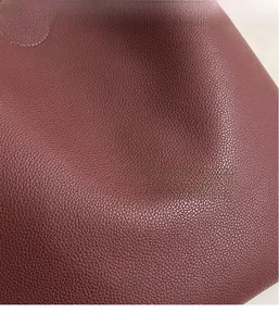 Detailed macro shot of dark burgundy pebbled PU leather with a silver metal buckle