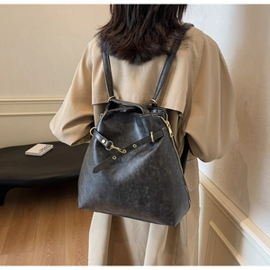 Detail of vintage black PU leather backpack showing side zipper and gold buckle on a model