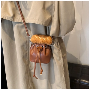 Detail of mini bucket bag with plush baguette trim and drawstring on brown leather
