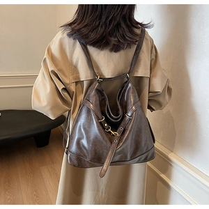 Detail of dark brown vintage PU leather backpack with metallic hooks and slim straps