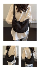Detail of black nylon crescent bag showing adjustable wide strap and woven zipper puller