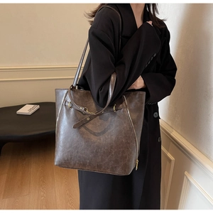 Detail of vintage dark brown tote bag showing textured leather and side decorative zippers