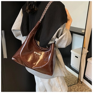 Dettaglio della borsa hobo in vernice marrone scuro con elegante tracolla a catena in metallo