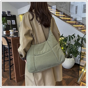 Detail view of sage green quilted crossbody bag showing spacious design and nylon texture