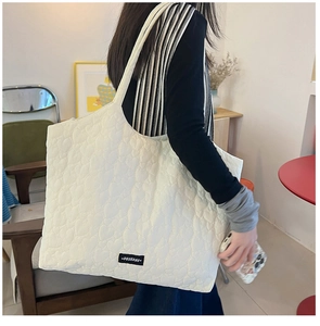 Detailed view of heart-shaped quilting pattern and brand tag on a white tote bag