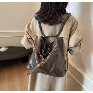 Detail of a dark brown vintage PU leather backpack with adjustable straps and brass hardware