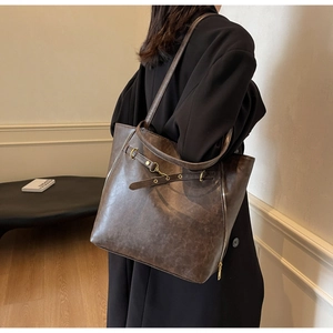 Detail of vintage dark brown tote bag featuring metallic buckles and textured faux leather