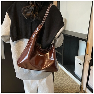 Dettaglio della borsa hobo in ecopelle bordeaux lucida con ornamento in metallo argento sulla spalla