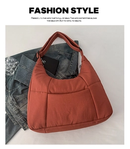 Flat lay of a large brick-red quilted puffer tote bag on a denim jacket background
